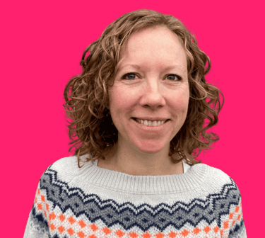 photo of woman with curly hair wearing a patterned jumper, on a pink background