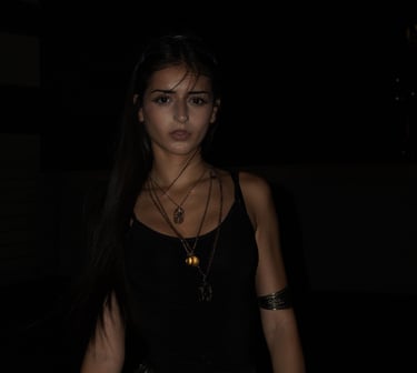 Miami lifestyle portrait of a woman in black tank top with layered gold necklaces at night