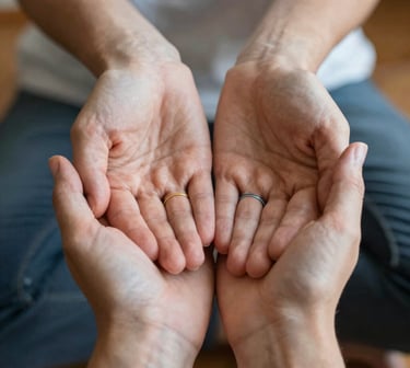 A couple wearing wedding bands holding hands together in a gesture of support and partnership.