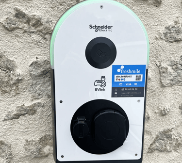 Borne électrique de recharge Schneider vu de face sur un mur en pierre