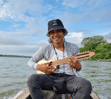 Roger Bardales playing a charango instrument on a boat on the Laguna Yarinacocha.