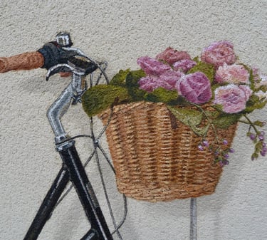 Détails d'un panier de vélo contenant des fleurs, peint en trompe-l'oeil sur une façade.