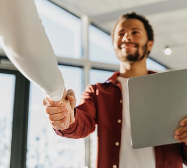 um homem e uma mulher apertando as mãos em uma reunião