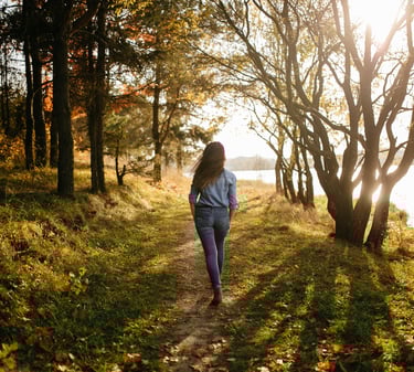 a woman walking down a path in the woods
