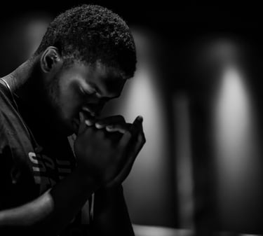 black & white photo of a Black man crossing his hands in prayer