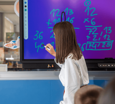 Teacher using the TICTIC interactive whiteboard app to deliver visual lessons with touch-enabled tools in a smart classroom.