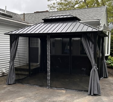 A 10 x 12 gazebo assembled with mosquito netting and privacy curtains