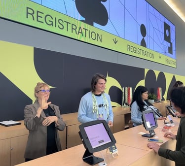 a sign language interpreter and a group of people at a registration booth for a conference