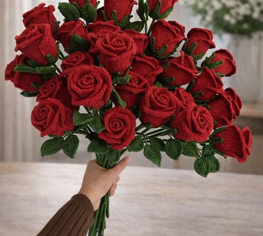Handmade crochet red rose bouquet with green leaves held in hand indoors