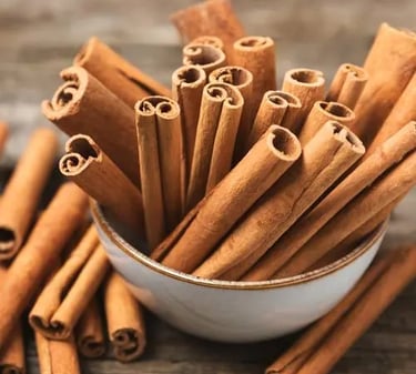 A small ceramic bowl filled with organic cinnamon sticks on a rustic wooden table.