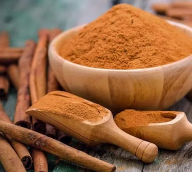 Organic ground cinnamon powder in a wooden bowl with cinnamon sticks and scoops on a rustic table.
