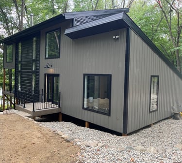 Annick Building Custom Construction, a small house with a black roof and a black roof