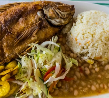 a plate of food with beans, white rice and fried fish