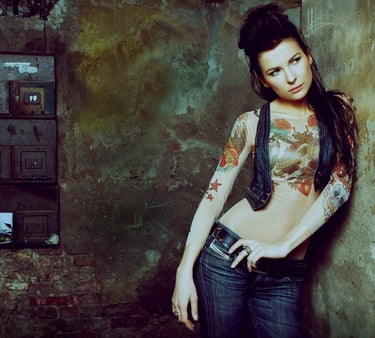 Audrius Turskas photography a woman with tattoos on her chest standing next to old textured wall