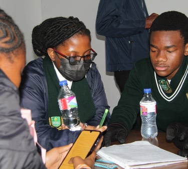 High school students in uniforms collaborating on a school project with notebooks and a smartphone.