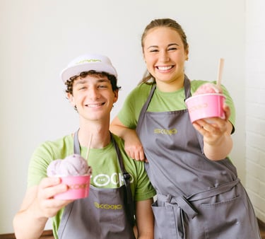 The Lafayette Scoop team male and female holding pink hard serve ice cream cups in Scoop logo