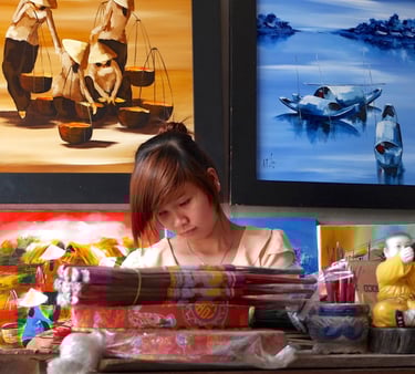 a woman sitting at a desk with a lot of art work