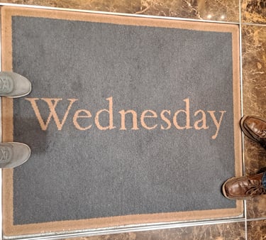 Two pairs of feet around a rug that says "Wednesday"