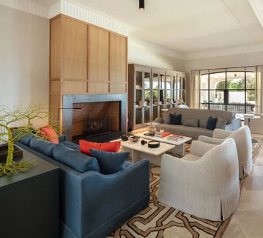 Seating area at Villa La Gratitud with designer sofas, fireplace, and garden views through windows. 