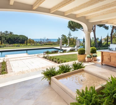 View from the shaded porch across the pool, with the Mediterranean Sea visible in the background.