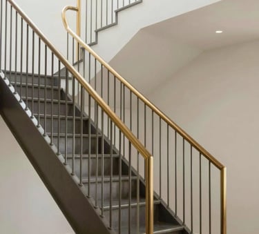 Detailed architectural photography of a minimalist luxury residential steel staircase with gold-toned handrails, clean industrial lines, soft natural light, North American / Mexican modern home interior.