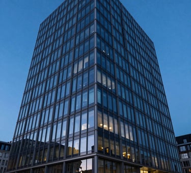 The exterior of a modern architectural building in a European / French business district at twilight, with deep royal blue sky reflections on its glass facade.