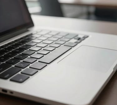 A close-up photograph of a sleek, professional silver laptop keyboard and trackpad, soft focus on the background, natural morning light in a modern Italian office setting, high-end and clean aesthetic.