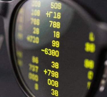 A close-up photograph of a high-tech digital interface reflected in a dark, polished eye-glass lens. The reflection shows sharp neon yellow data patterns against a pitch-black background.