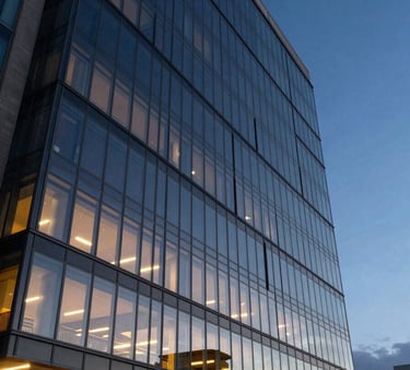 A sharp, cinematic architectural shot of a modern glass building in Joinville during twilight, reflecting deep ocean blue sky with warm sun yellow internal lights.