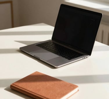 A minimalist and bright workspace in Southern France, featuring a sleek laptop on a cream-colored desk, a terracotta-colored notebook, and soft shadows from a nearby window, professional photography style.
