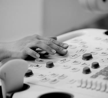 Ultrasonographer with hand on machine keyboard, operating controls.