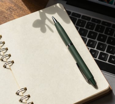 A top-down aesthetic shot of a creative workspace featuring a Crisp Parchment notebook, a Matte Forest Green pen, and a laptop displaying social media analytics, surrounded by natural morning light.