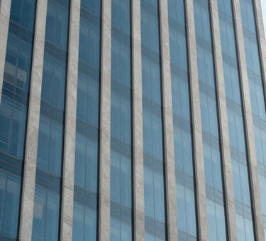 A sharp, detailed photograph of a North American / US skyscraper facade reflecting a clear sky. The composition is geometric and minimalist, highlighting the sophisticated and trustworthy nature of a modern financial institution, featuring shades of Steel Blue and Light Gray.