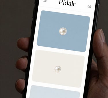 A close-up of a modern smartphone held in a hand, displaying a sleek, minimalist website interface with Pearl White and Dusty Sky Blue accents.