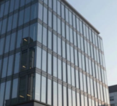 A sleek, modern commercial office building with glass windows reflecting a clear blue sky, emphasizing refined professionalism and architectural reliability, featuring tones of #1E272C and #A5B6C0.