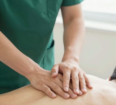 Close-up of professional hands performing a precise manual therapy technique on a patient. Soft, natural lighting highlighting a clean clinical environment with muted green (#4C706F) and off-white (#F5F8F7) tones.