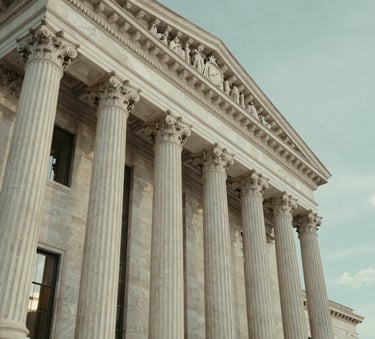 A low-angle shot of a courthouse exterior with grand stone columns under a soft, muted sage teal sky, reflecting authority and principled law.