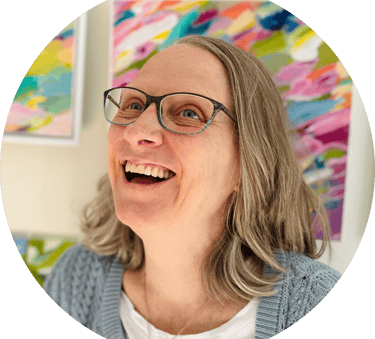 Portrait of artist smiling with colorful abstract painting behind her