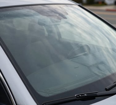 Wide shot of a pristine, high-end vehicle windshield reflecting a clear sky in a North American coastal town. The glass is perfectly clean and sharp, symbolizing the silver standard of repair. The aesthetic is modern and reliable.