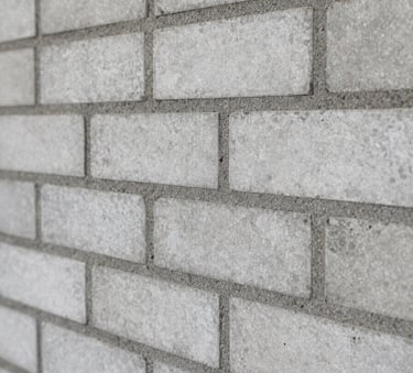 Close-up detail of high-quality masonry work, showcasing perfectly aligned rows of bricks and clean mortar joints, grey and light grey tones, professional architectural photography, Sul Americano / Brasileiro style.