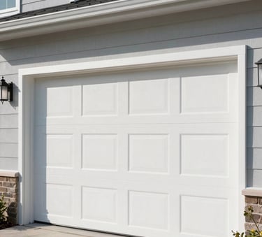 A close-up photograph of a modern, insulated white garage door being installed on a contemporary North American home during a bright, clear day. The focus is on the clean lines and high-quality finish of the panels.