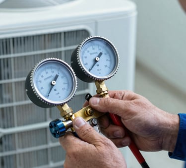 A close-up photograph of a professional technician's hands using a gauge to check the pressure of an HVAC unit in a North American / US residential setting. The scene uses Steel Blue and Powder Blue tones, reflecting unwavering professionalism and expertise.