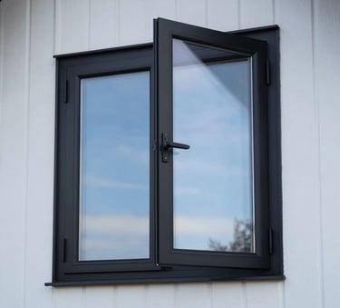 Detailed shot of sleek black-wrapped window frames on a minimalist Northern European home, reflecting a clear blue sky, premium and modern finish.