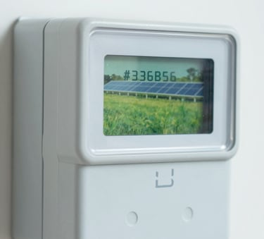 A close-up shot of a modern digital electricity meter showing a reduced reading, with a soft reflection of a lush green field and solar panels in the glass, professional photography, clean and bright lighting, incorporating colors like #326B5E and #8ECFC4.