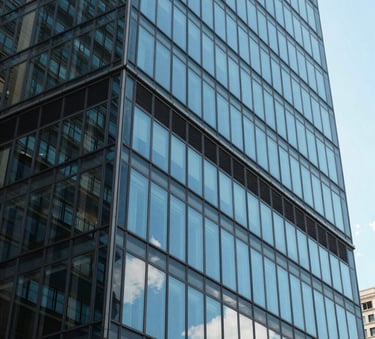 A close-up of a modern glass office building reflecting a bright blue sky, North American / Global Business environment, professional and clean architectural photography.