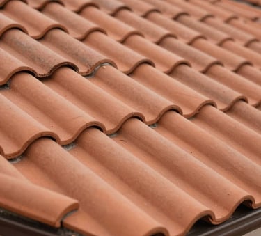 A close-up photograph of perfectly aligned terracotta roof tiles on a house, highlighting professional installation and clean lines, natural daylight, European / French residential architecture.