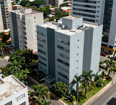 A sharp, high-angle photograph of a modern residential neighborhood in a South American city, featuring clean architecture and lush green landscaping, bright natural daylight, shades of light blue-gray and slate blue.