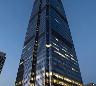 Wide angle photography of a modern glass skyscraper in a South Asian financial district at dusk, warm interior lights reflecting against a deep blue sky, authoritative and corporate atmosphere.