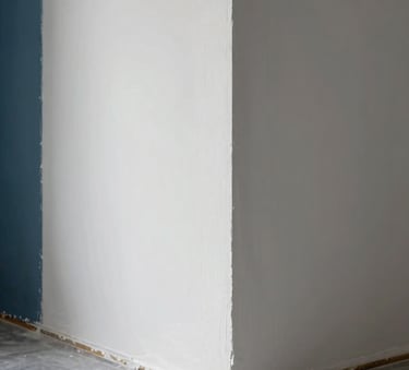A close-up photograph of high-end interior renovation work, showing a perfectly plastered corner meeting a sleek floor, with Muted Steel Blue accents in the lighting and Crisp Arctic White walls.