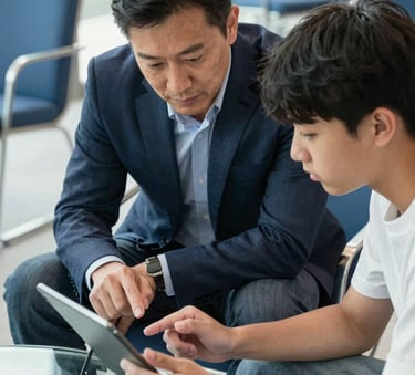 A close-up shot of a professional mentor and a college student reviewing a digital tablet together in a bright, modern lounge with steel blue chairs and clean glass surfaces.